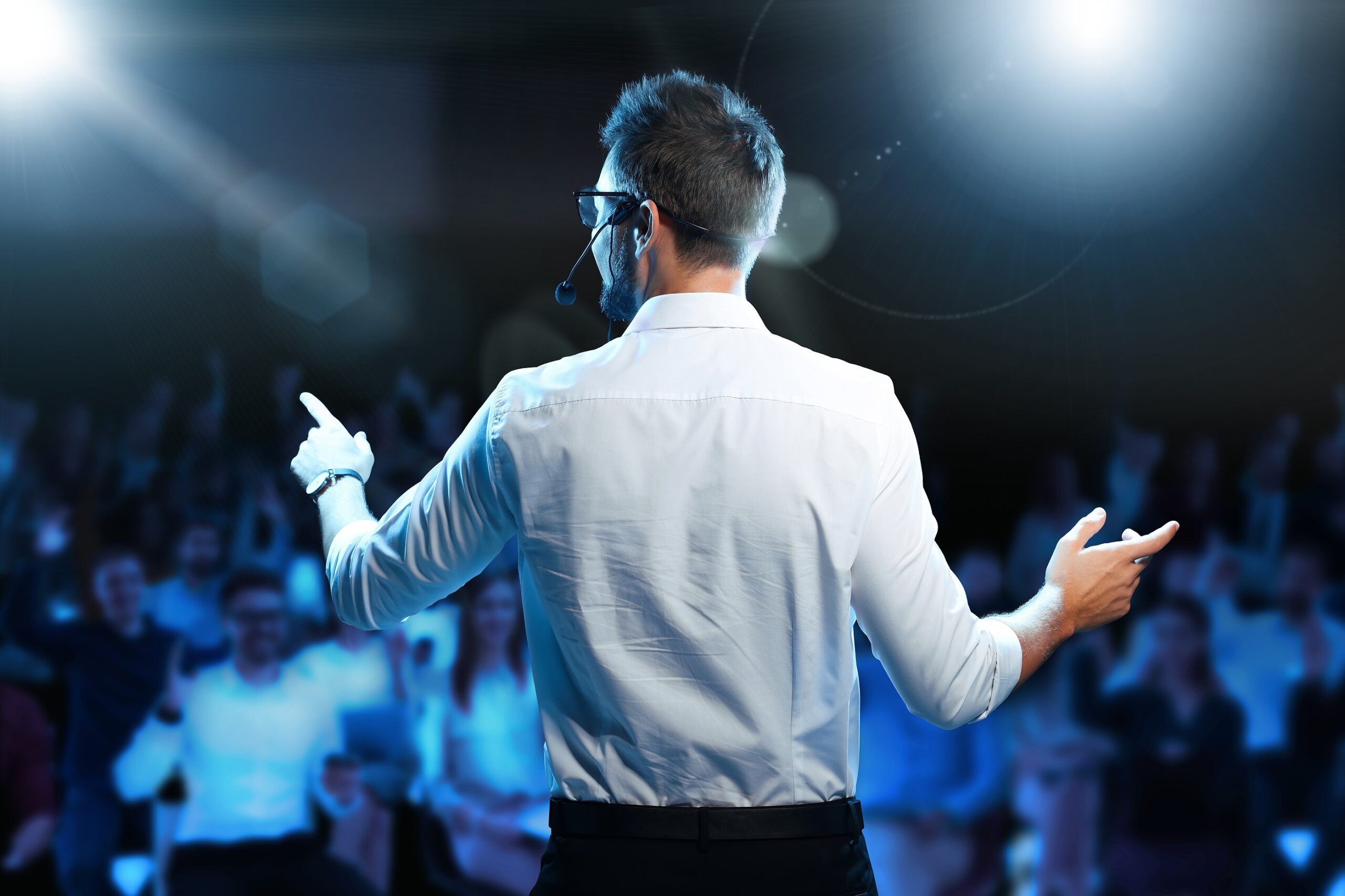 motivational speaker with headset performing on stage, back view