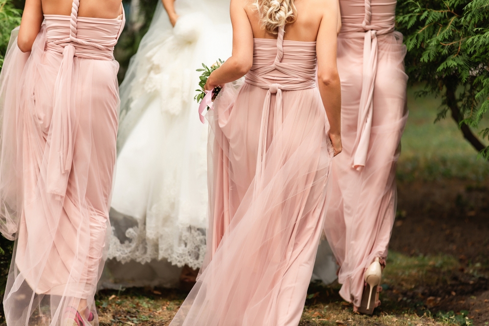 bride,and,bridesmaids,in,pink,dresses,walking,at,wedding,day.