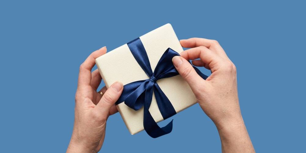 top,view,of,hands,holding,a,small,white,gift,box